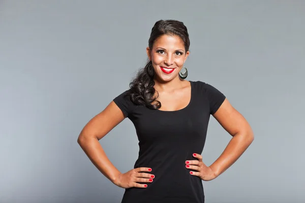 Menina bonita com cabelo castanho e olhos vestindo vestido preto. Batom vermelho e esmalte vermelho. Boa aparência. Gala. Retrato de estúdio isolado sobre fundo cinza . — Fotografia de Stock