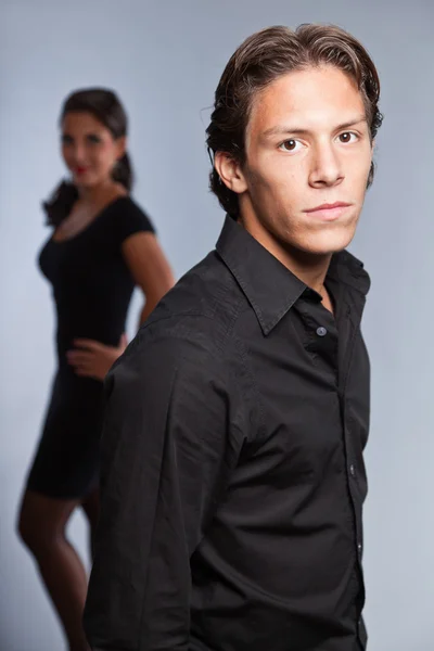 Pretty young couple dressed in black. Brother and sister. Good looking. Brown hair and eyes. Studio portrait isolated on grey background. — Stock Photo, Image