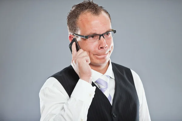 Angry young business man calling with mobile phone — Stock Photo, Image