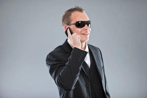 Glücklicher junger Geschäftsmann telefoniert mit Handy mit kurzen Haaren trägt dunklen Anzug mit weißem Hemd und lila Krawatte. — Stockfoto