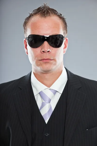 Jeune homme d'affaires agressif aux cheveux courts portant un costume sombre avec chemise blanche et cravate violette . — Photo