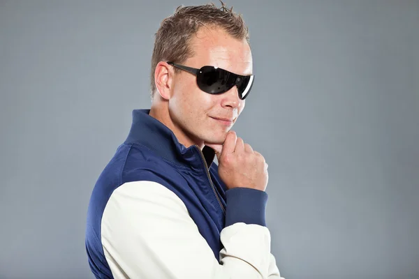 Joven feliz con el pelo corto usando chaqueta de béisbol azul y vaqueros azules . — Foto de Stock