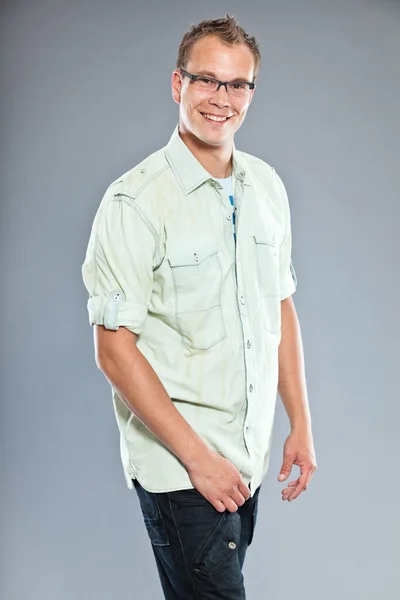 Jovem feliz com cabelo curto vestindo camisa verde claro e jeans azul . — Fotografia de Stock