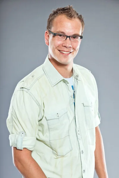 Glücklicher junger Mann mit kurzen Haaren trägt hellgrünes Hemd und blaue Jeans. — Stockfoto