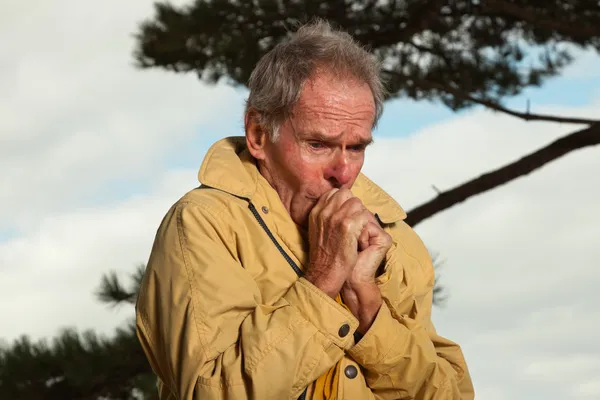 Senior man with yellow coat. Having cold. — Stock Photo, Image