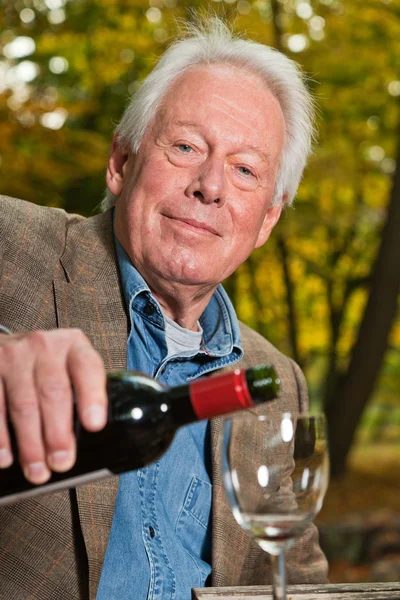 Homme âgé dégustant du vin rouge en plein air dans la forêt d'automne . — Photo