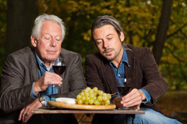 kırmızı şarap ve peynir keyfi kıdemli ve genç bir adam.