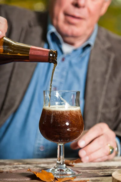 Homme âgé dégustant de la bière noire et du fromage à l'extérieur . — Photo