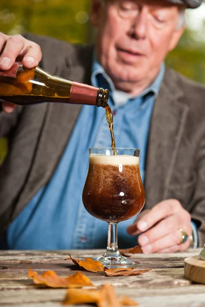 Homem sênior desfrutando cerveja escura e queijo ao ar livre . — Fotografia de Stock