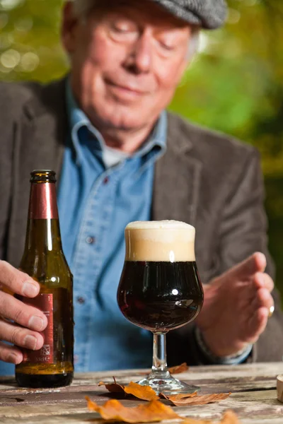 Homme âgé dégustant de la bière noire et du fromage à l'extérieur . — Photo