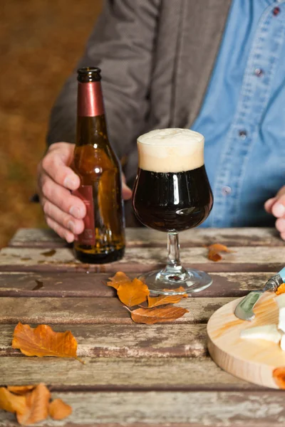 Senior genießt dunkles Bier und Käse im Freien. — Stockfoto