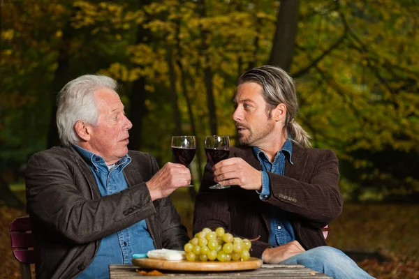 Senior en jonge man genieten van rode wijn en kaas. — Stockfoto
