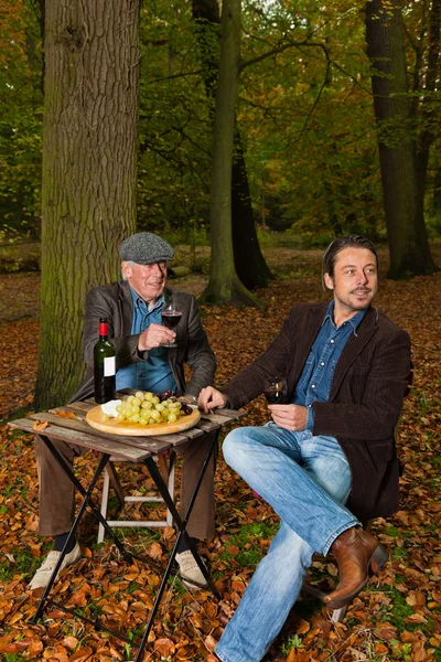 Senior e jovem desfrutando de vinho tinto e queijo . — Fotografia de Stock