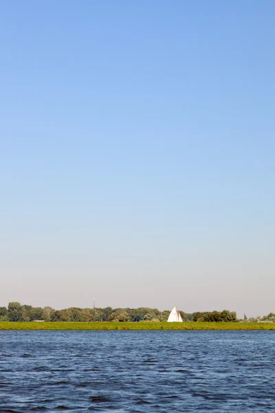 荷兰景观与湖和树木和孤独的帆船。夏天与蓝蓝的天空. — 图库照片