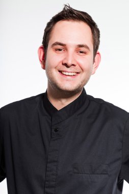 genç erkek aşçı siyah üzerine beyaz izole ceket yemek yapıyor..