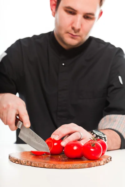 Jonge mannelijke kok met zwarte koks jas geïsoleerd op wit. — Stockfoto