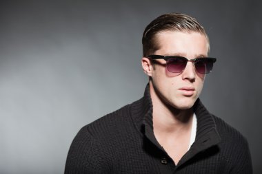 moda stüdyo portre yakışıklı genç adamın gri bir arka plana dayanır.