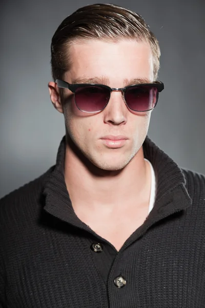 Mode studio portret van knappe jonge man tegen een grijze achtergrond. — Stockfoto