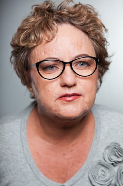 kısa kıvırcık saçlı kadın kıdemli. gri arka planı vurdu studio.