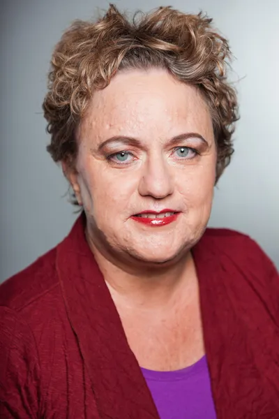 Senior woman with short curly hair. Studio shot against grey background. — Stock Photo, Image