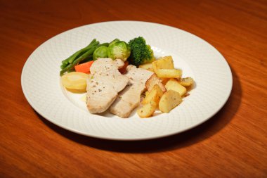 yemek sebze patates ve et tabağı ve ahşap masa.