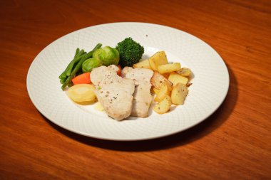 yemek sebze patates ve et tabağı ve ahşap masa.