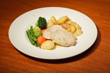 yemek sebze patates ve et tabağı ve ahşap masa.