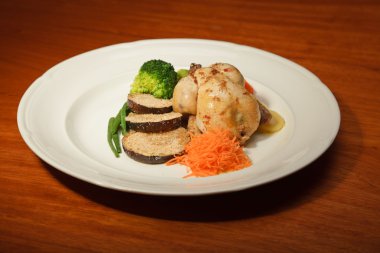 ahşap masa ve bir tabak tavuk ve sebze yemeği.