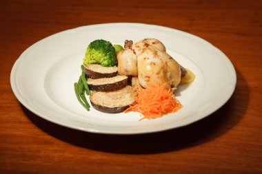 ahşap masa ve bir tabak tavuk ve sebze yemeği.