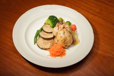 ahşap masa ve bir tabak tavuk ve sebze yemeği.