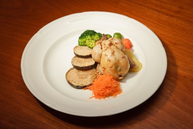 ahşap masa ve bir tabak tavuk ve sebze yemeği.