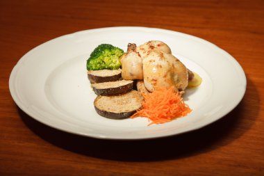 ahşap masa ve bir tabak tavuk ve sebze yemeği.