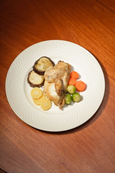 Ужин из овощей и курицы на тарелке и деревянном столе . — стоковое фото