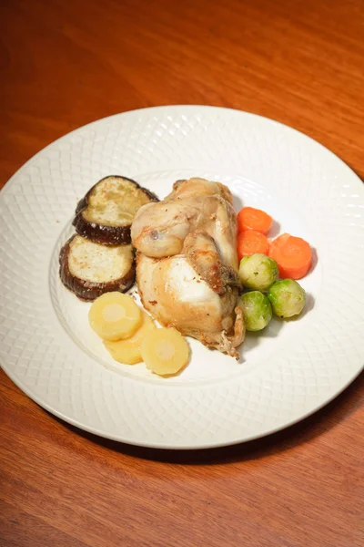 Ужин из овощей и курицы на тарелке и деревянном столе . — стоковое фото