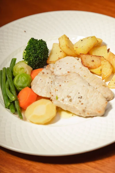 Abendessen mit Gemüse Kartoffeln und Fleisch auf einem Teller und Holztisch. — Stockfoto