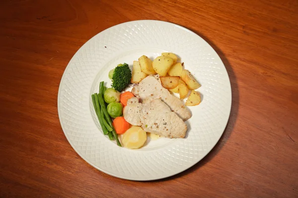 Abendessen mit Gemüse Kartoffeln und Fleisch auf einem Teller und Holztisch. — Stockfoto