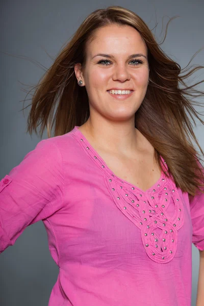 Pretty brunette woman with long hair against grey. — Stock Photo, Image