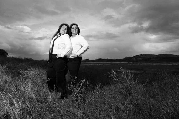 Two women with black hair outdoors with dark sky. — Stock Photo, Image