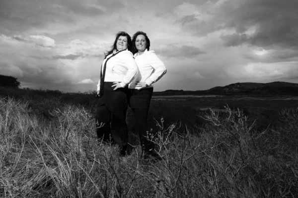 Two women with black hair outdoors with dark sky. — Stock Photo, Image