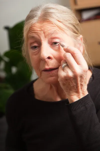 Senior woman doing make-up. — Stock Photo, Image