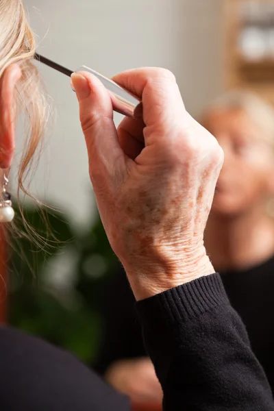Seniorin schminkt sich. — Stockfoto