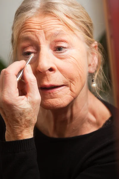 Senior woman doing make-up. — Stock Photo, Image