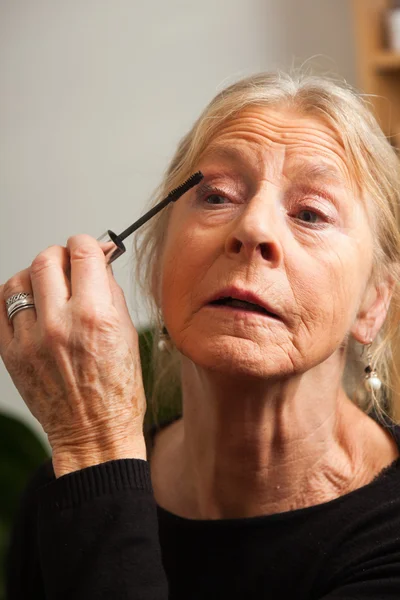 Senior woman doing make-up. — Stock Photo, Image