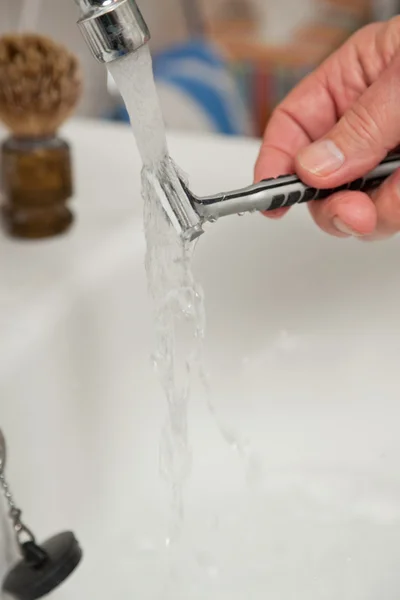 Closeup of hand cleaning shaving blade. — Stock Photo, Image