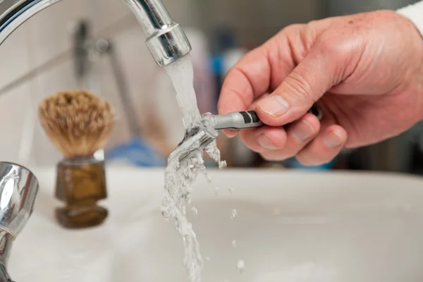 Closeup of hand cleaning shaving blade. — Stock Photo, Image