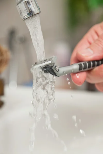 Zbliżenie dłoni czyszczenia ostrza do golenia. — Zdjęcie stockowe