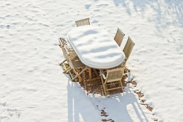 Mobília de jardim de madeira coberta com neve . — Fotografia de Stock