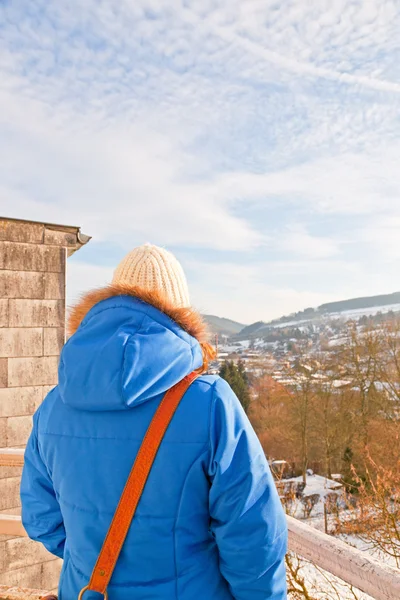 Woman from back looking over village in snow valley. — Stock Photo, Image