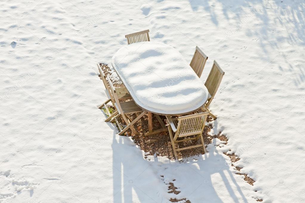 Wooden garden furniture covered with snow.