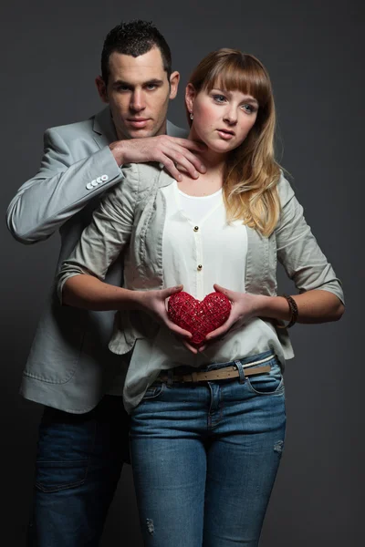 Mysterious young couple in love holding red heart. — Stock Photo, Image
